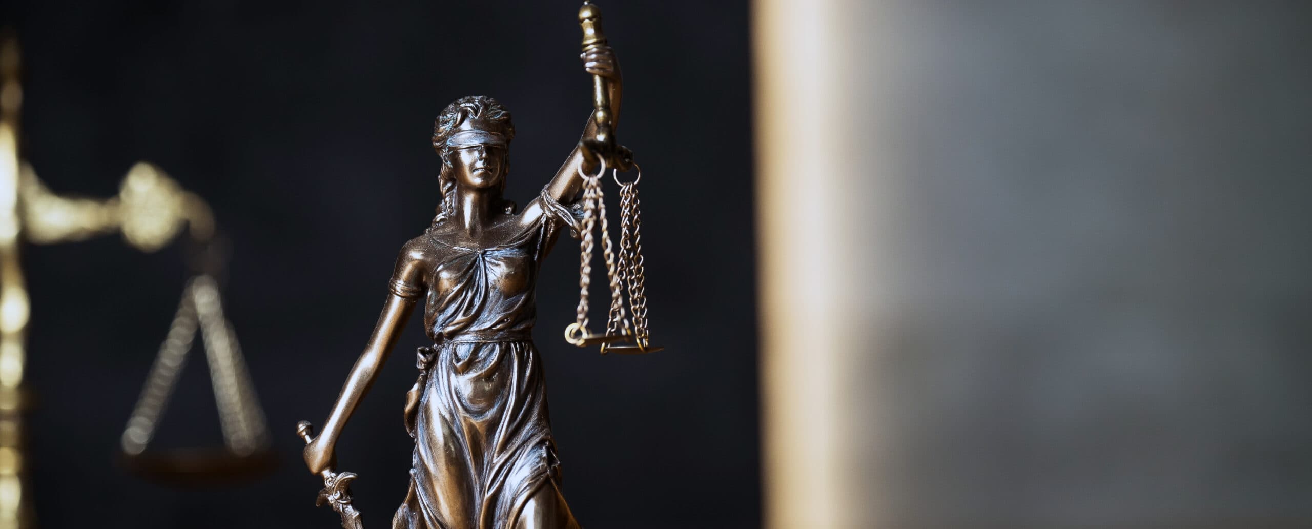 Statue de la déesse de la justice tenant une balance en équilibre sur fond sombre